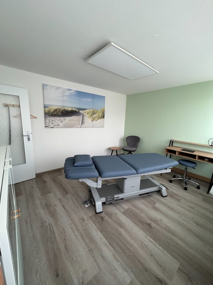 Behandlungsraum mit Therapieliege, Stuhl und hellem, freundlichem Ambiente.
