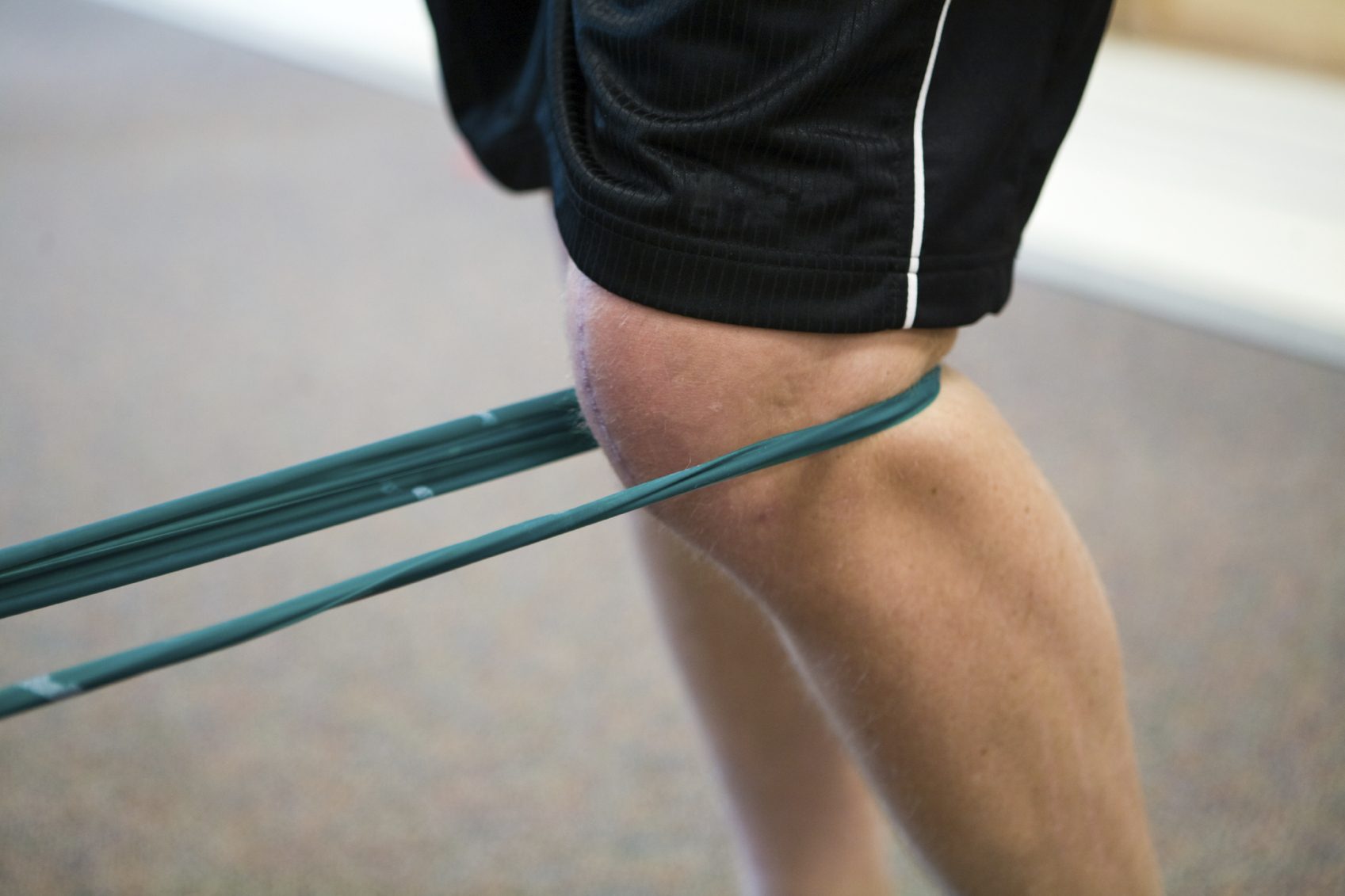Person mit einem Widerstandsband, das am Knie befestigt ist, während er trainiert.